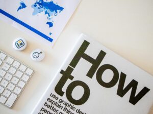 Stylish desk setup with a how-to book, keyboard, and world map on paper.