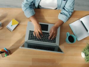 Top-down view of a person working on a laptop at a neat desk with accessories.