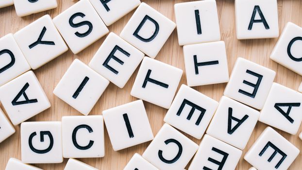 Closeup of scattered scrabble tiles against a wooden background, ideal for word games and learning themes.